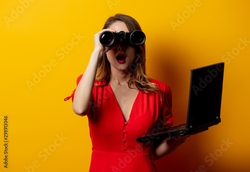  woman in red dress with binocular and laptop computer