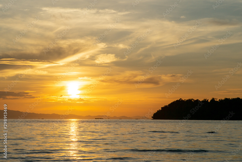 Landscape of sea with silhouette of island and orange light of sunrise Landscape of sea with silhouette of island and orange light of sunrise