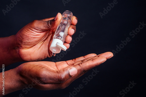 Картината върху платно close up hands of afro male useing antiseptic in studio black background