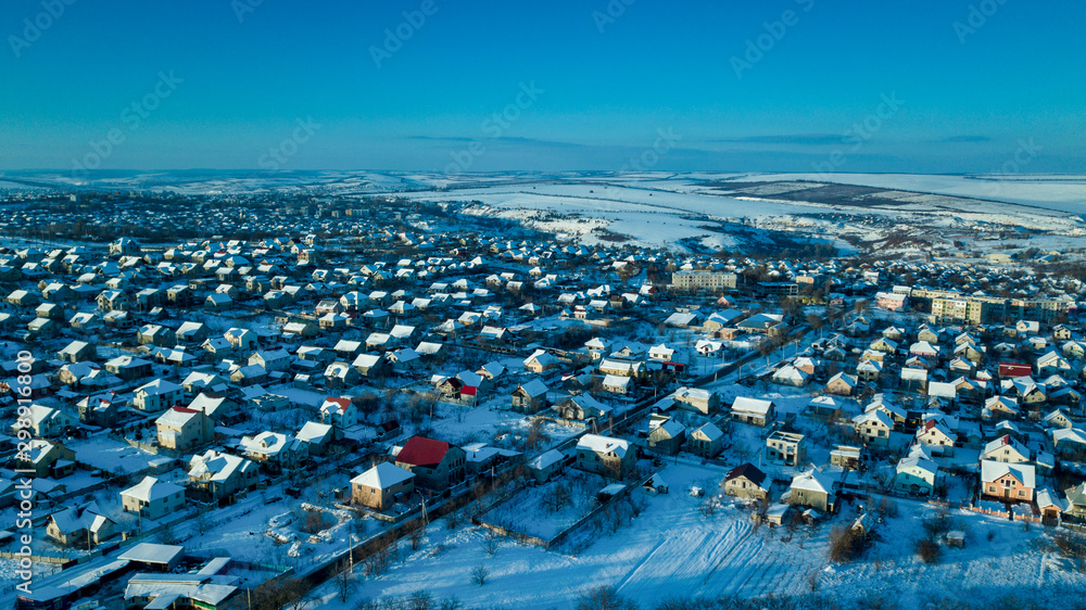 Fototapeta premium aerial view village among the fields and forests in winter. winter landscape snow covered field and trees in countryside.
