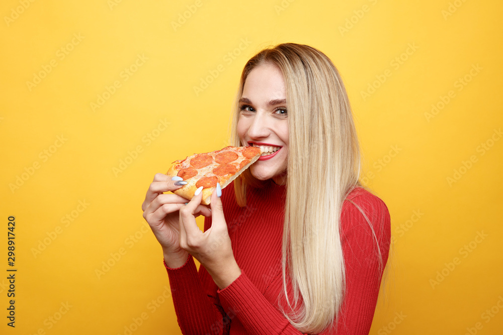 Happy woman eating tasty pizza for lunch in the pink studio - obrazy, fototapety, plakaty 