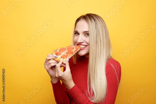 Happy woman eating tasty pizza for lunch in the pink studio