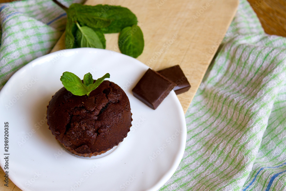 Top View of Chocolate Muffin with Mint Leaves on the Saucer in the Kitchen Top View of Chocolate Muffin with Mint Leaves on the Saucer in the Kitchen