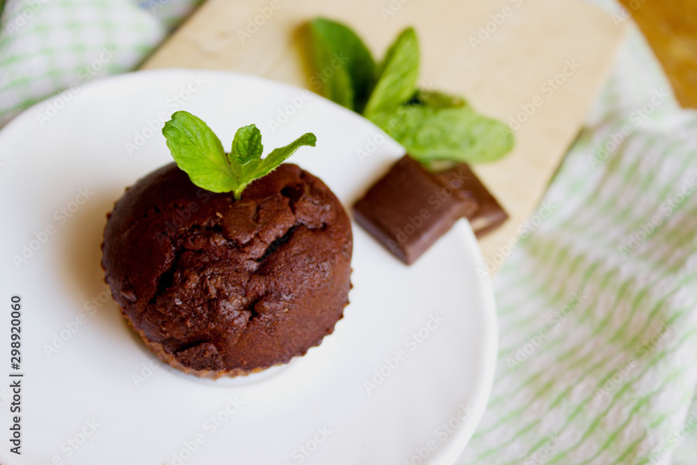 Top View of Chocolate Muffin with Mint Leaves on the Saucer in t Top View of Chocolate Muffin with Mint Leaves on the Saucer in t