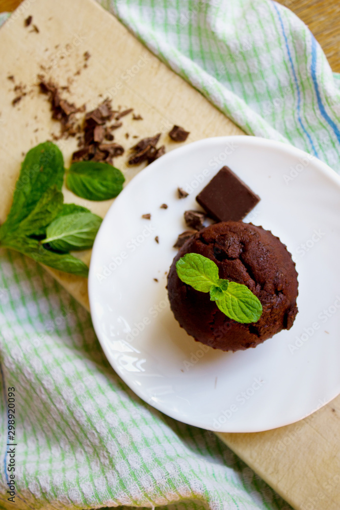 Top View of Chocolate Muffin with Mint Leaves on the Saucer in t Top View of Chocolate Muffin with Mint Leaves on the Saucer in t
