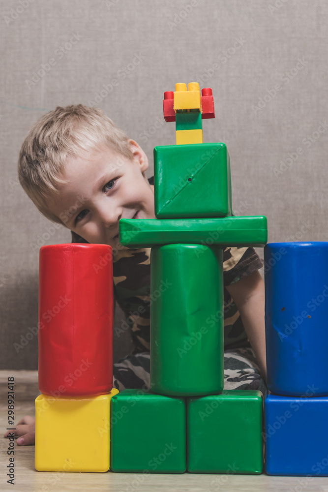 little boy enthusiastically plays with multi-colored plastic cubes little boy enthusiastically plays with multi-colored plastic cubes