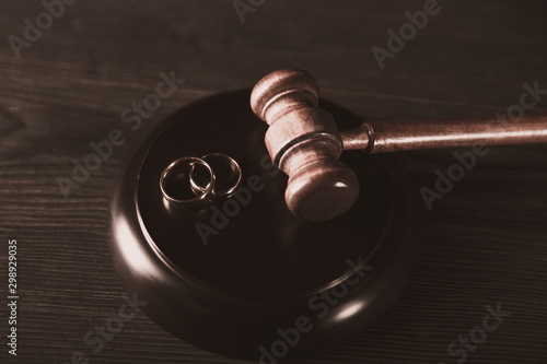 Brown judje wooden gavel and wedding rings on the table. Divorce process concept photo