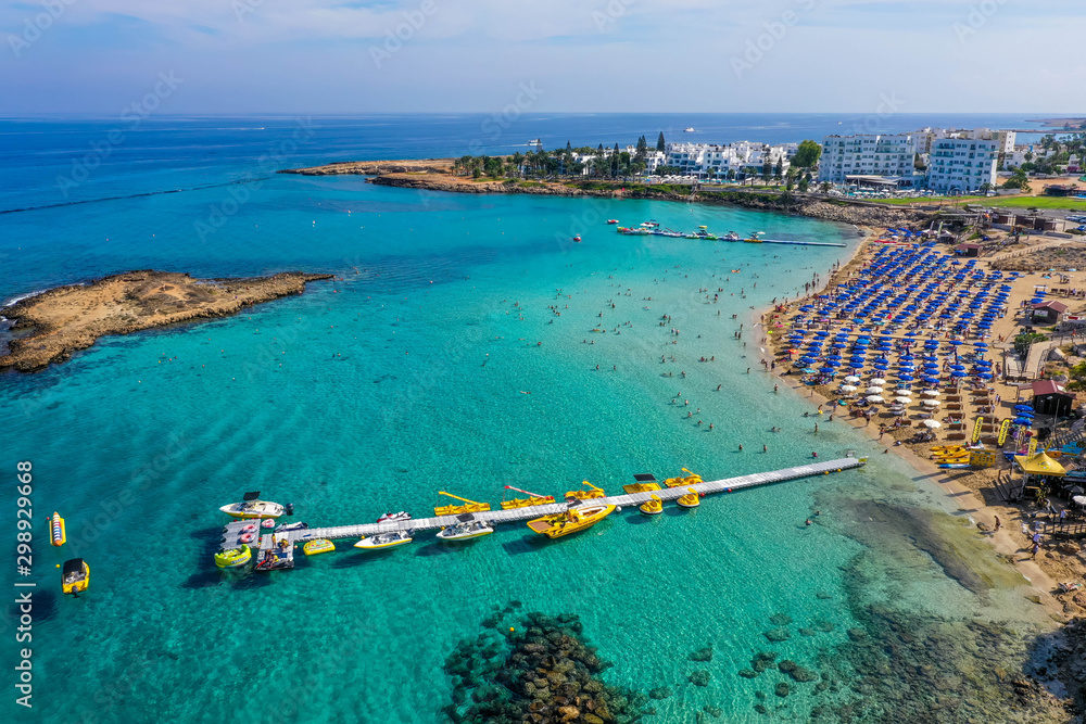 Water activities and pier on the turquoise sea water near the beach. Aerial view from above. Cyprus, Agia Napa