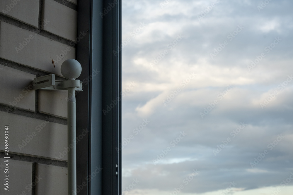 Part of a white plastic cornice for curtains, prepared for repair, against the background of a window through which the sky and clouds are visible Part of a white plastic cornice for curtains, prepared for repair, against the background of a window through which the sky and clouds are visible