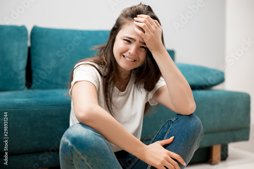 beautiful young woman crying feeling very depressed sitting on floor shouting loud with her hand touching her head tough life photo