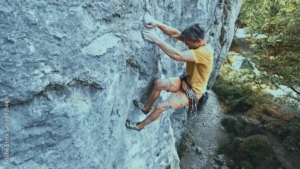 man rock climbing on tough sport route, rock climber makes a hard move