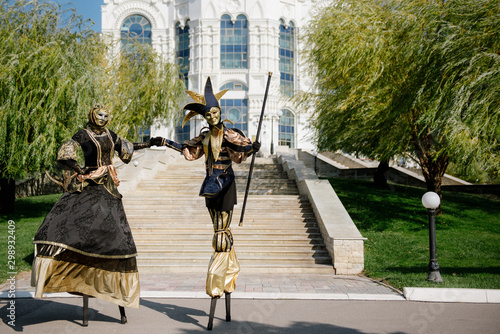 people on stilts in carnival costumes and fancy dress masks