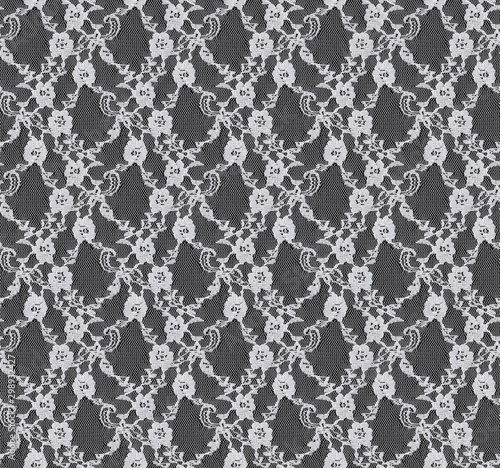 Seamless pattern in the form of white lace on a black background. Flower ornament. Tulle.