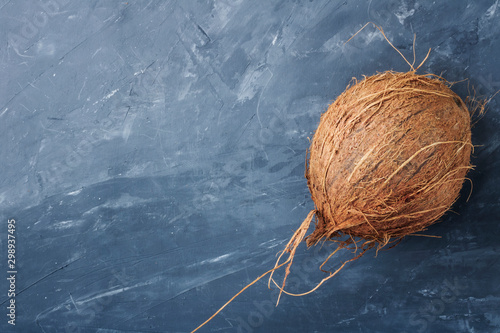 Whole natural coconuton isolated on gray blue concrete background. Top view, close-up. Copy space photo