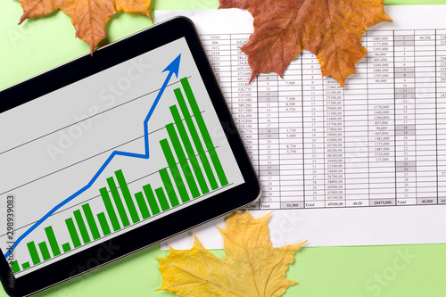 A tablet with a business graph on the desktop. Autumn leaves