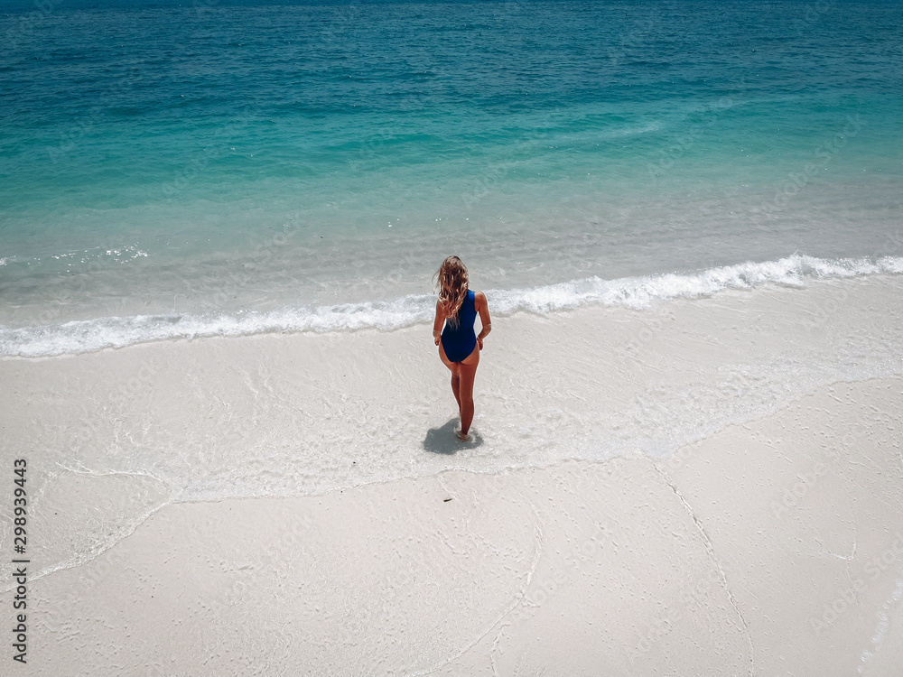 Beautiful girl in a good shape standing near the ocean enjoying breeze and its waves. Photo from above Beautiful girl in a good shape standing near the ocean enjoying breeze and its waves. Photo from above
