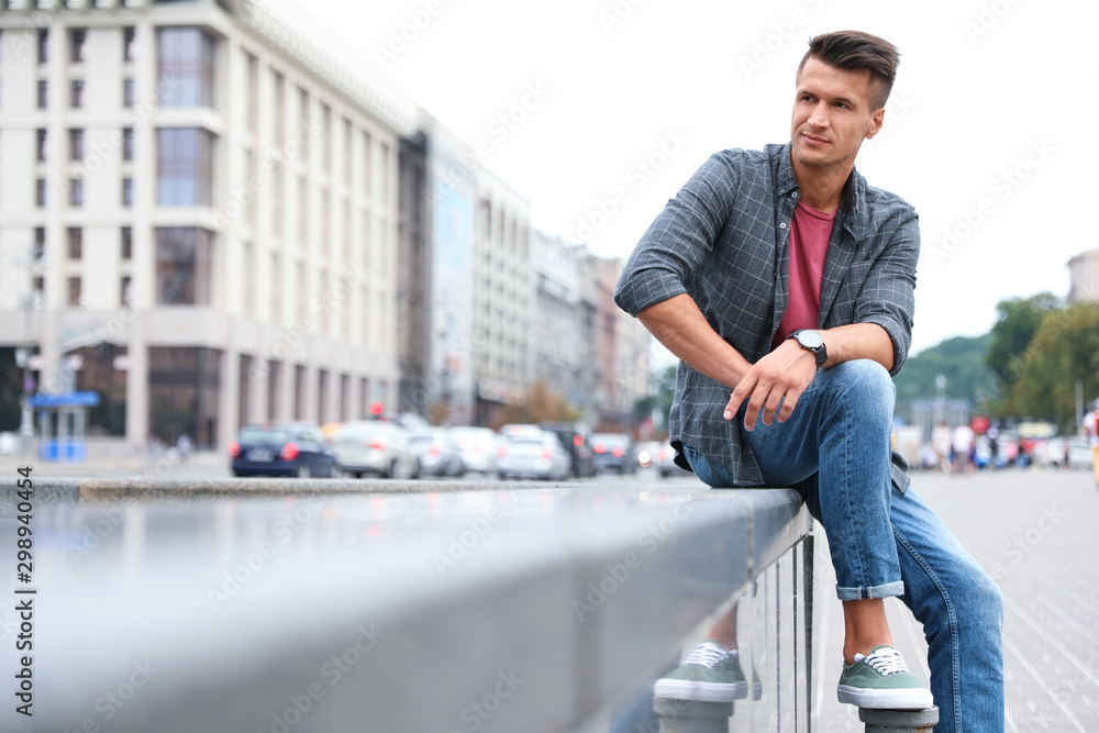 Portrait of handsome young man on city street. Space for text