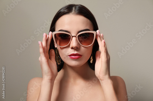 Beautiful woman in stylish sunglasses on beige background