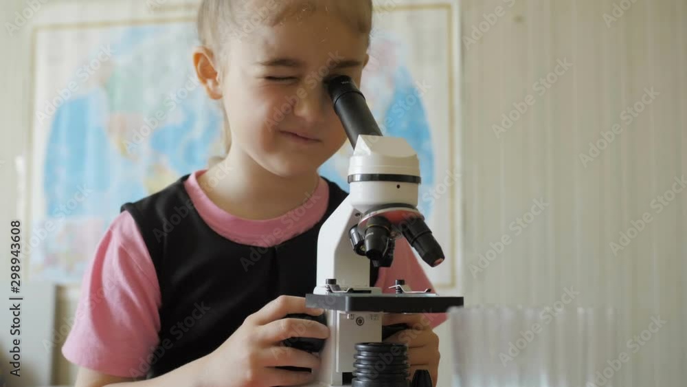 Little girl in science lab study samples under microscope. Schoolgirl looking through microscope in science class. Child looking into microscope, studing biology, chemistry in school laboratory. Little girl in science lab study samples under microscope. Schoolgirl looking through microscope in science class. Child looking into microscope, studing biology, chemistry in school laboratory.