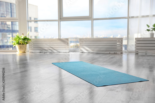 Unrolled light blue yoga mat on floor in room photo