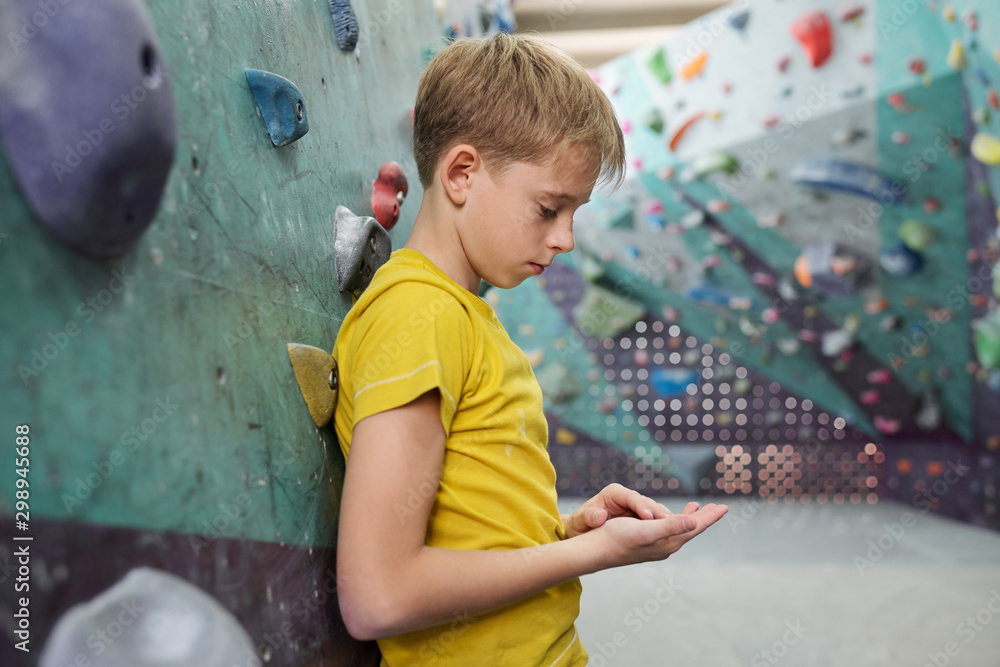 Obraz premium Tired or sad youngster in yellow t-shirt leaning against climbing equipment