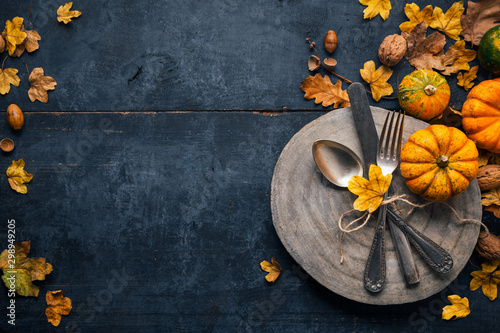 Thanksgiving background with cutlery, pumpkins and dry leaves