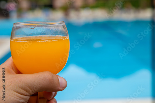 glass of orange juice on the background of the pool