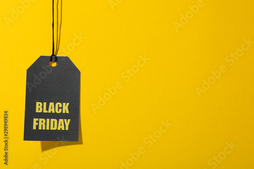 Inscription Black Friday on price tag on yellow background, copy space