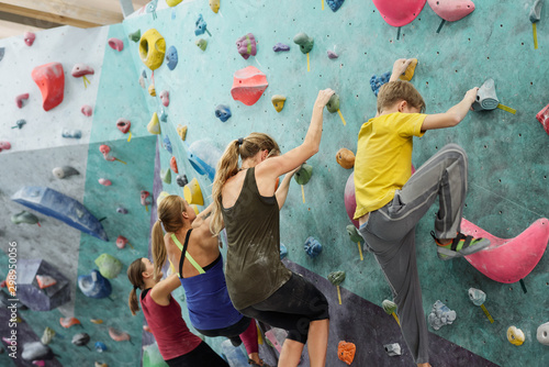 Young sportswomen and schoolboy in activewear creeping upon climbing wall
