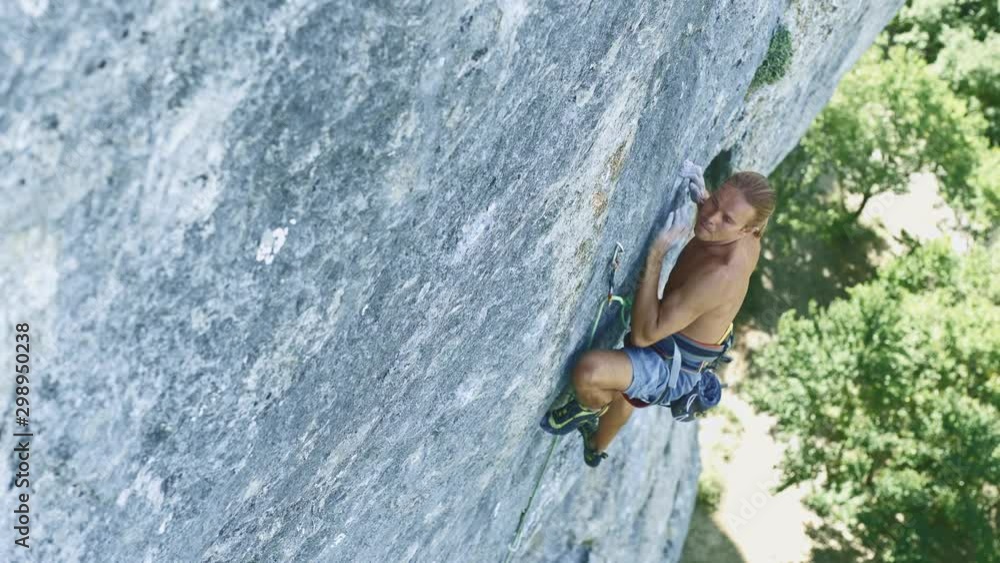strong muscular tanned man rock climber dynamically climbing on a limestone cliff, making hard wide move and gripping hold. outdoors rock climbing and active lifestyle concept, 4k stock footage strong muscular tanned man rock climber dynamically climbing on a limestone cliff, making hard wide move and gripping hold. outdoors rock climbing and active lifestyle concept, 4k stock footage