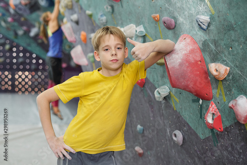 Cute boy showing thumb up while leaning by rock climbing equipment