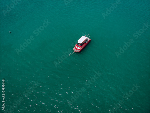 Drone view of the small brand-new red and white motorboat in blue sea, it shines in the bright sun; vessels concept.