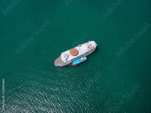 .Top view of the big old rusty motorboat, wooden deck, blue motorboat at one side  turquoise sea in a sunny day  types of vessels.. © Semachkovsky 