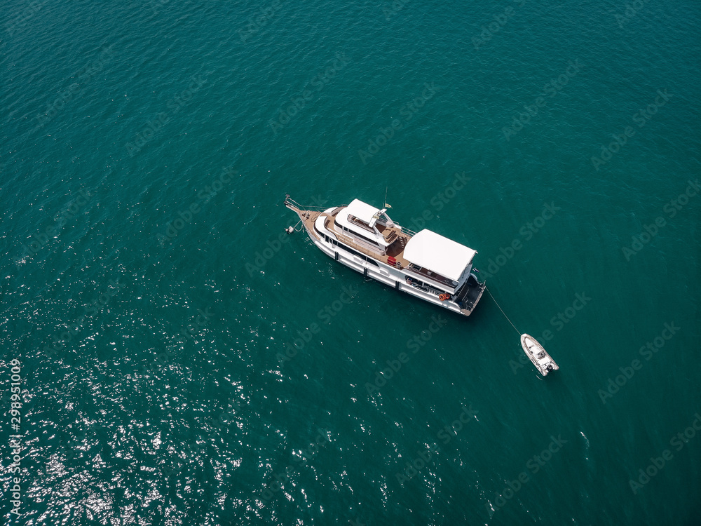 Aerial view of the big motor vessel with lifeboat, white sides and wooden deck; boats  concept.