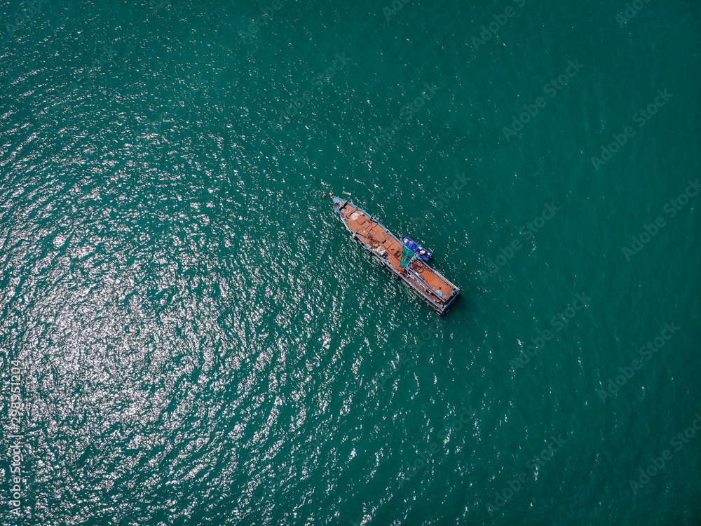 Drone view of the big old blue motorboat with huge empty deck in blue sea, violet lifeboat at its side; vessels concept. Drone view of the big old blue motorboat with huge empty deck in blue sea, violet lifeboat at its side; vessels concept.