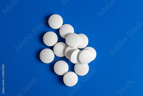 white round pills scattered blue background, chaotically scattered.