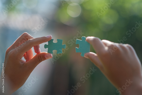 two hands hold puzzle pieces