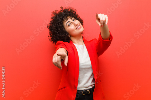 young pretty afro woman feeling happy and confident, pointing to camera with both hands and laughing, choosing you