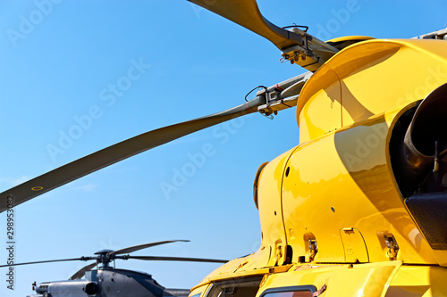 Yellow and black helicopter. Close up of helicopter main rotor blades against a blue sky with copy space.