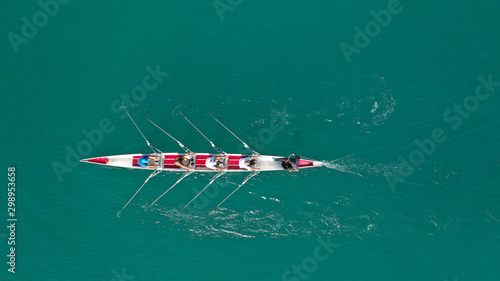 Aerial drone bird's eye view of sport canoe operated by team of young women in deep blue sea waters