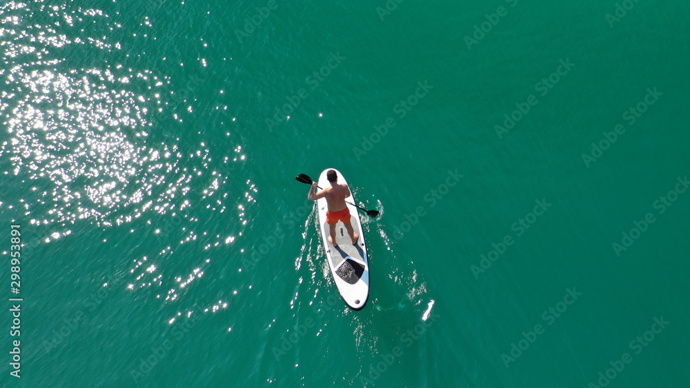 Fototapeta premium Aerial drone photo of man exercising sup paddle board in tropical exotic lake with emerald waters
