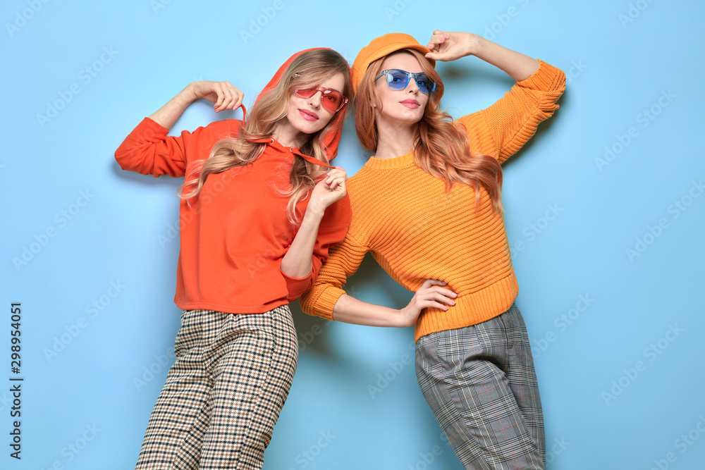 Two easy-going happy hipster Woman smiling in Stylish fashion orange colored outfit. Beautiful Girl in Trendy sweatshirt, cap. Joyful sister, friend, Creative fashionable friendship concept Two easy-going happy hipster Woman smiling in Stylish fashion orange colored outfit. Beautiful Girl in Trendy sweatshirt, cap. Joyful sister, friend, Creative fashionable friendship concept