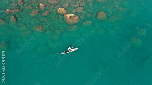 Aerial drone photo of man exercising sup paddle board in tropical exotic lake with emerald waters