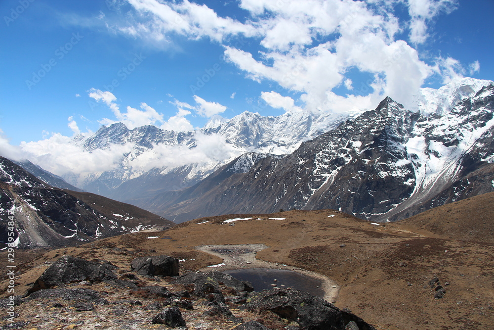 Obraz premium Plain with dried grass and mountain peaks in the background near Lunden village in the Himalayas in Nepal. Sagarmatha national park, route to the Everest base camp through Gokyo lakes.
