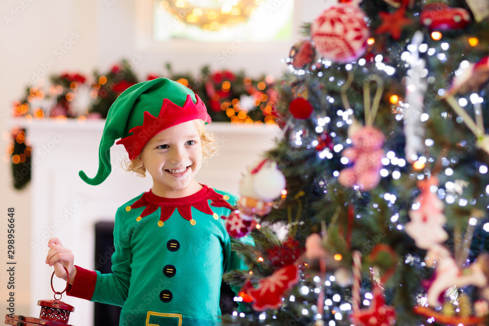 Child decorating Christmas tree. Kid on Xmas eve. - obrazy, fototapety, plakaty 