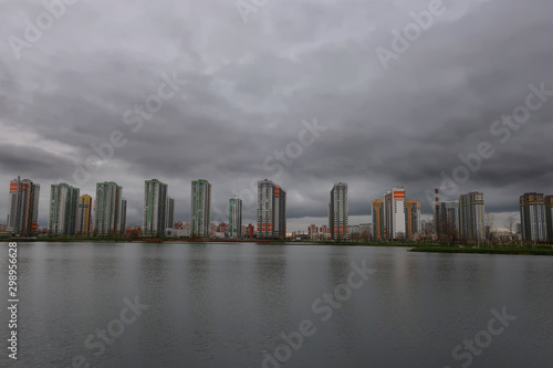 residential complex of high-rise buildings on the banks of the pond in inclement weather © Sergey