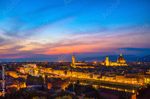 Top aerial panoramic evening view of Florence city with Duomo Santa Maria del Fiore cathedral, Arno river, Ponte Vecchio bridge and Palazzo Vecchio palace at night dusk, city lights, Tuscany, Italy