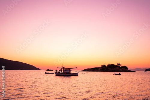 fishing boat with greece flag, beautiful sunrise on background