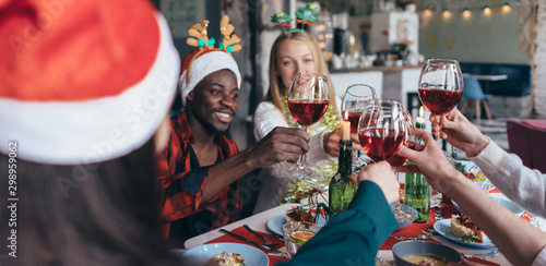 Schilderij op canvas Friends celebrating Christmas or New Year eve clink glasses sitting at the table