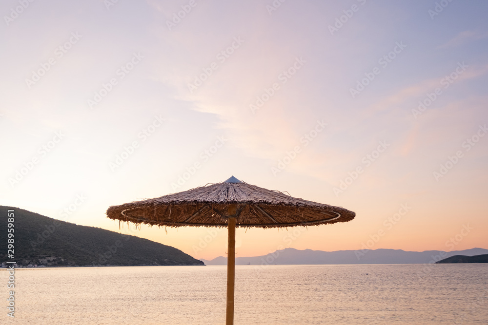 Beach umbrella in the Greece, landscape with beautiful sunrise and summer beach